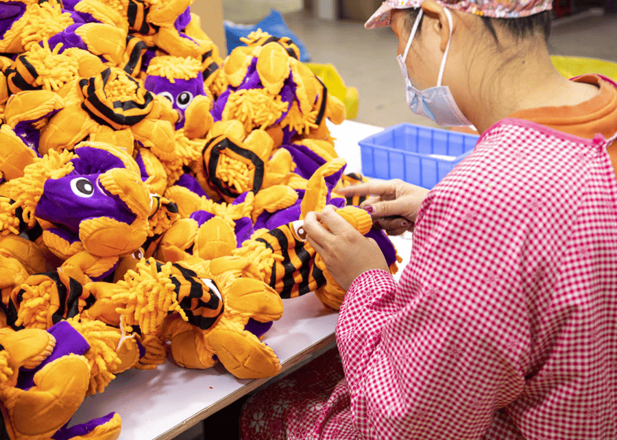 An inspector checking a line of plush dog toys for quality