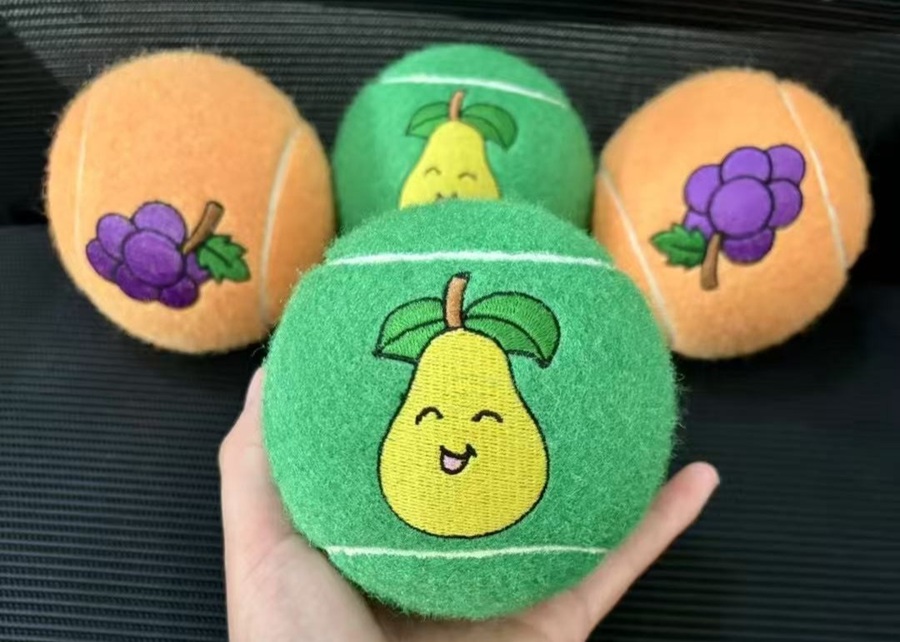 A display of custom-branded dog tennis balls with different logos and colors.