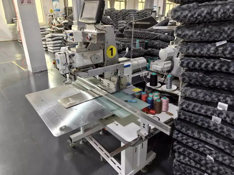 Sewing station with stacked pet bed covers in a factory workshop