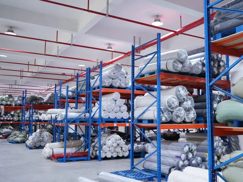 Rolls of fabric and materials stored on racks for pet home product production