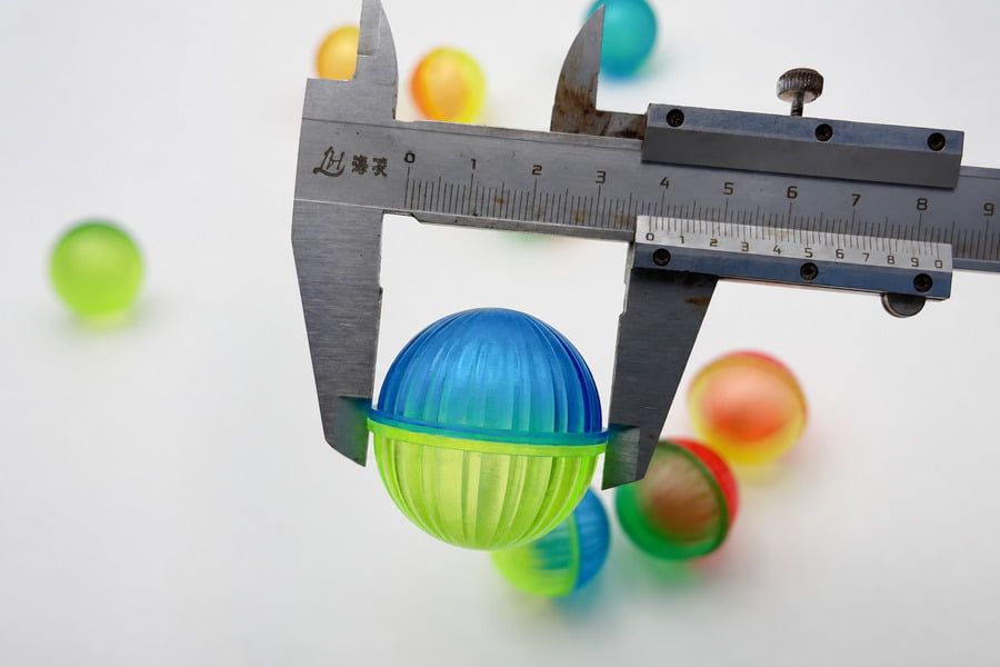Plastic cat ball being measured with a vernier caliper during quality inspection