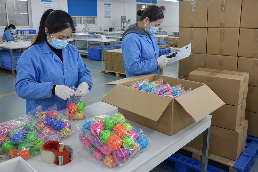 Workers packing cat ball toys and checking cartons before shipment