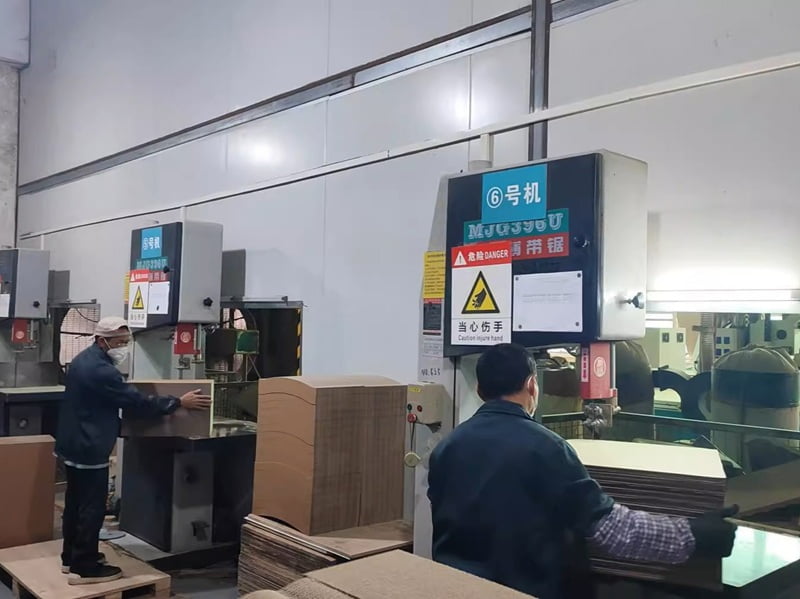 Workers cutting laminated corrugated blocks into shaped cat scratcher components