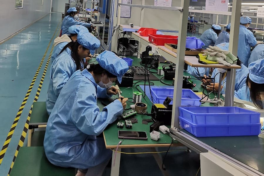 Workers assembling and soldering electronic components on a production line