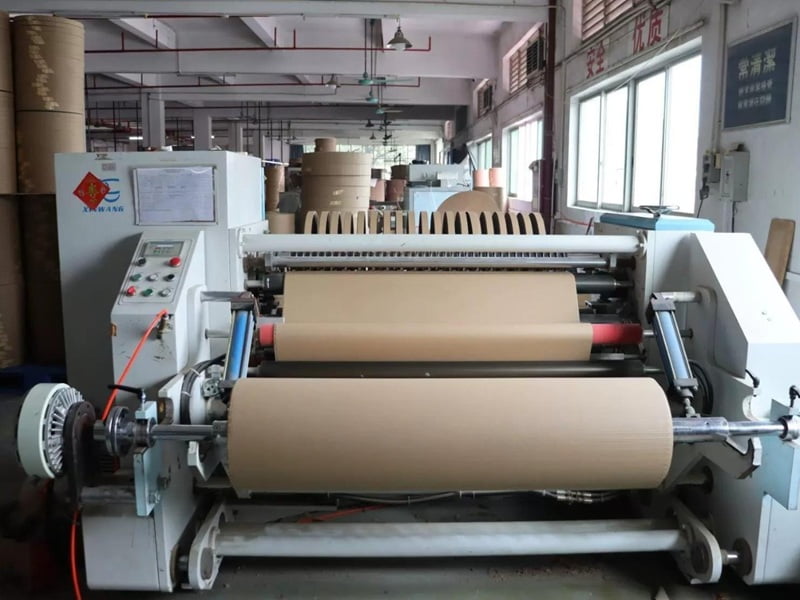 Paper rolls being prepared on production equipment for corrugated cat scratcher manufacturing