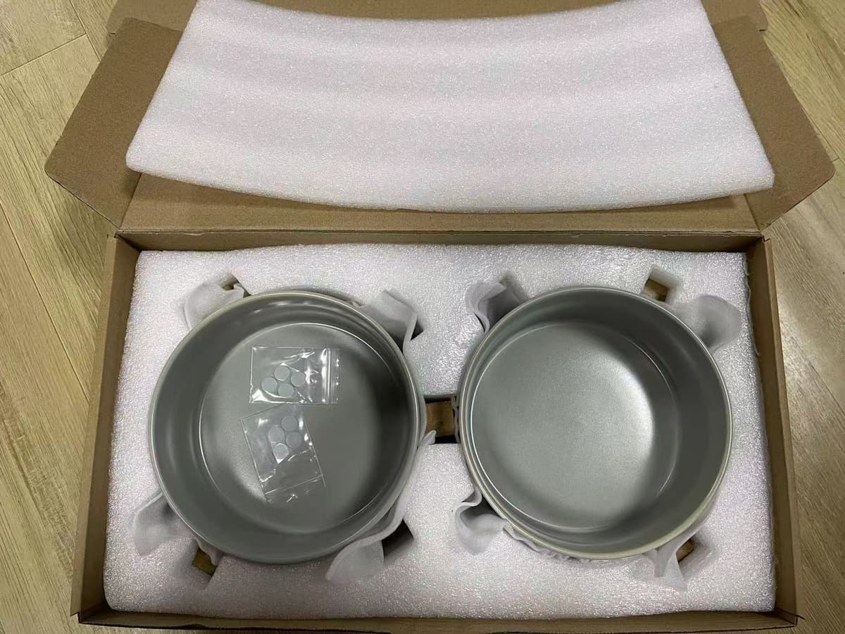 Two gray ceramic pet bowls secured in fitted foam inserts inside an open kraft box