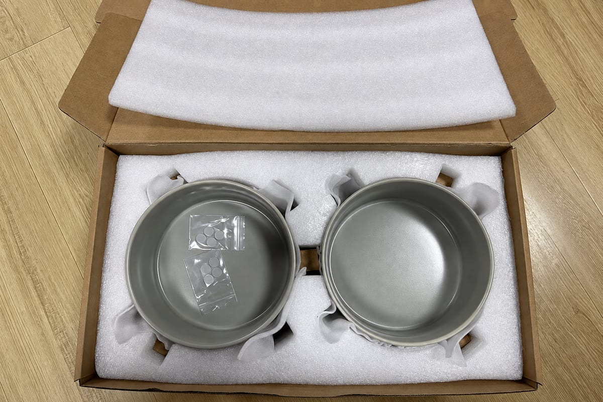 Two gray ceramic pet bowls packed in a cardboard box with fitted foam inserts