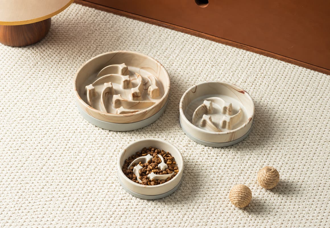 Ceramic slow feeder bowls in three sizes with raised curved partitions and a beige marble pattern