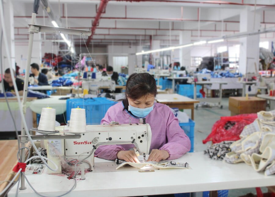 Worker sewing a dog harness at an industrial sewing machine in the workshop.
