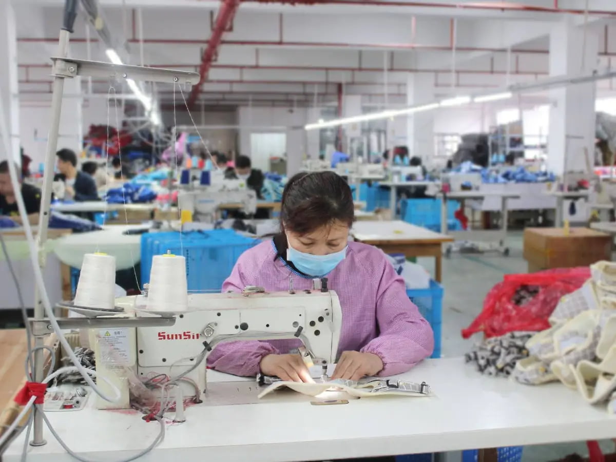 Worker sewing a pet walking accessory at an industrial sewing machine