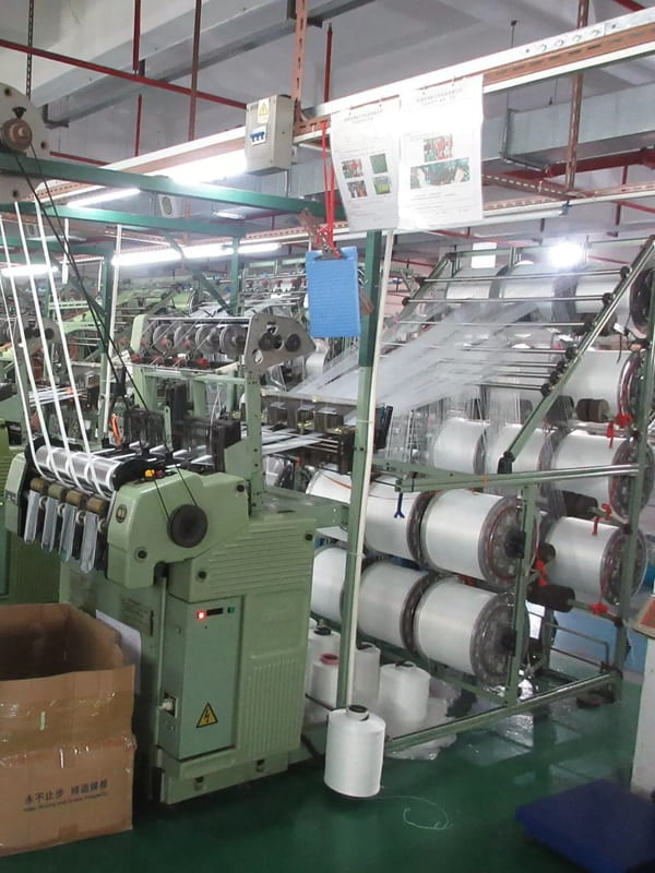 Rows of weaving machines producing white webbing for pet collars