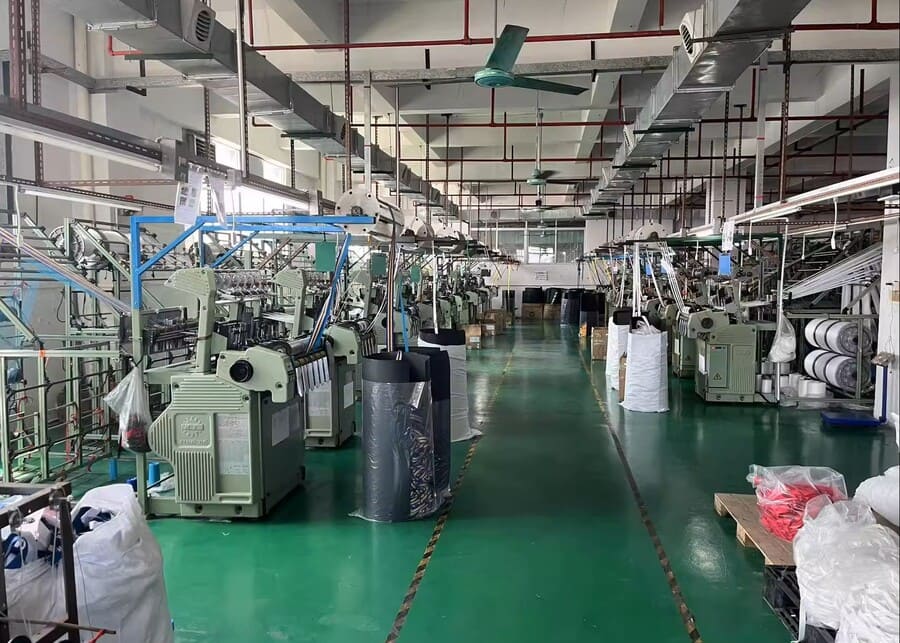 Factory workshop with rows of webbing production machines.