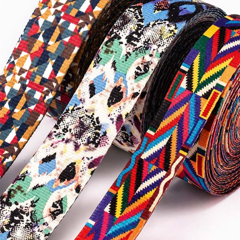 Rolls of printed polyester webbing with colorful geometric and animal-print patterns for pet harness straps.